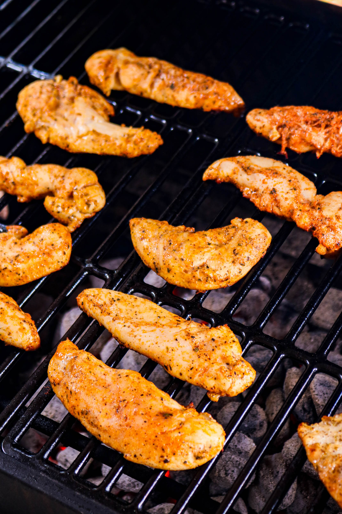 Chicken tenders cooking on bbq grates.
