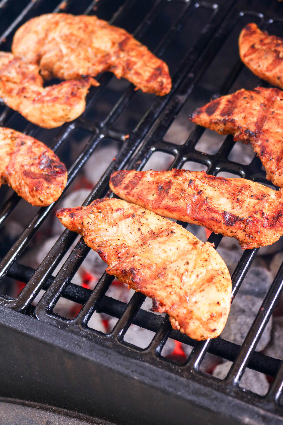 Grilled chicken tenders on grate with grate cooking marks.