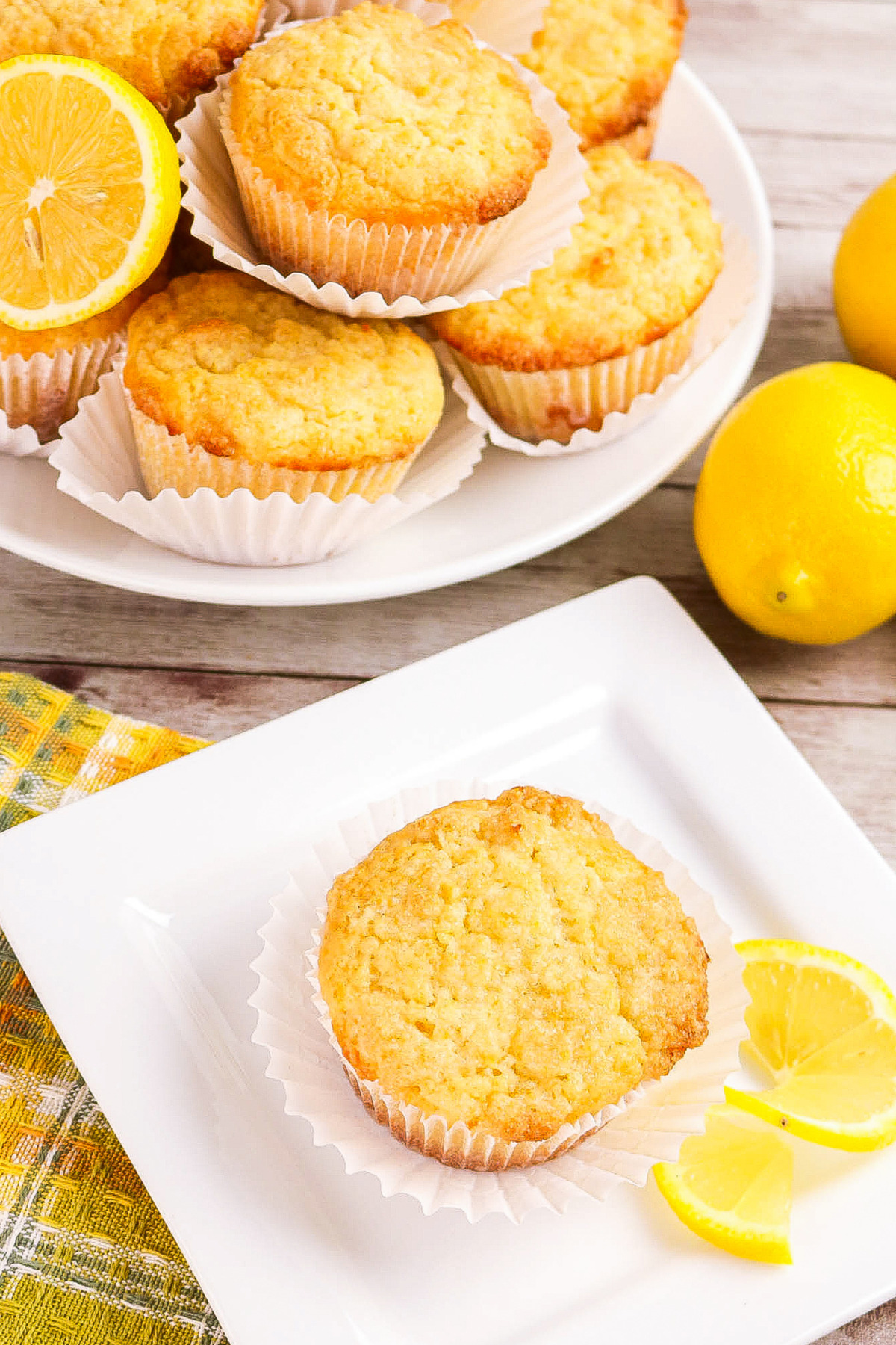 Top view of a muffin on a plate with a platter of muffins on the side.
