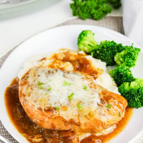 Slow cooker chicken French onion soup on a white plate with brocolli on the side.