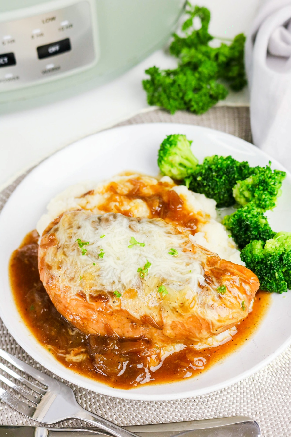 Slow cooker chicken French onion soup on a white plate with brocolli on the side.
