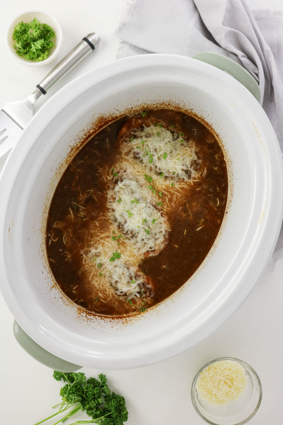 Overhead view of chicken in a french onion soup made in a slow cooker.