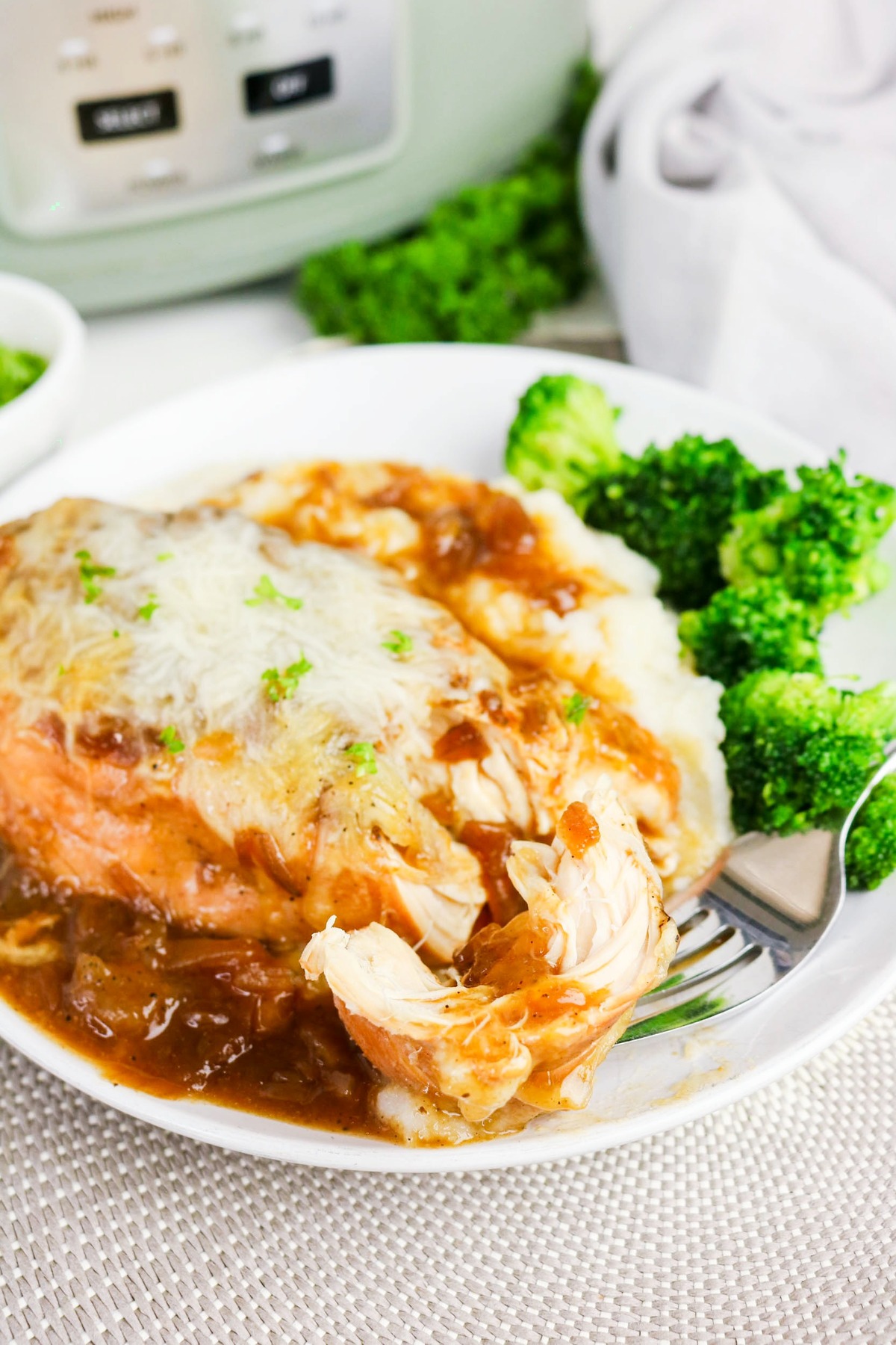 A fork full of chicken from a plated white dish.