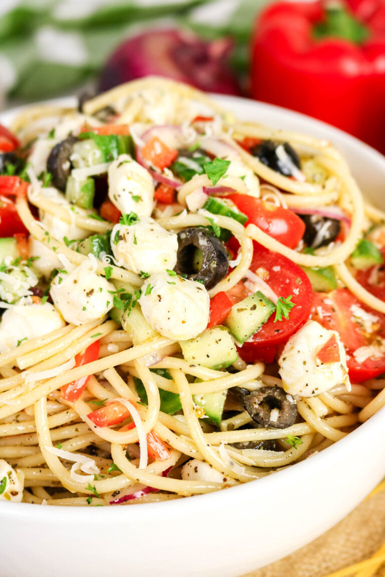 Cold pasta salad with greek inspired ingredients in a white serving bowl.