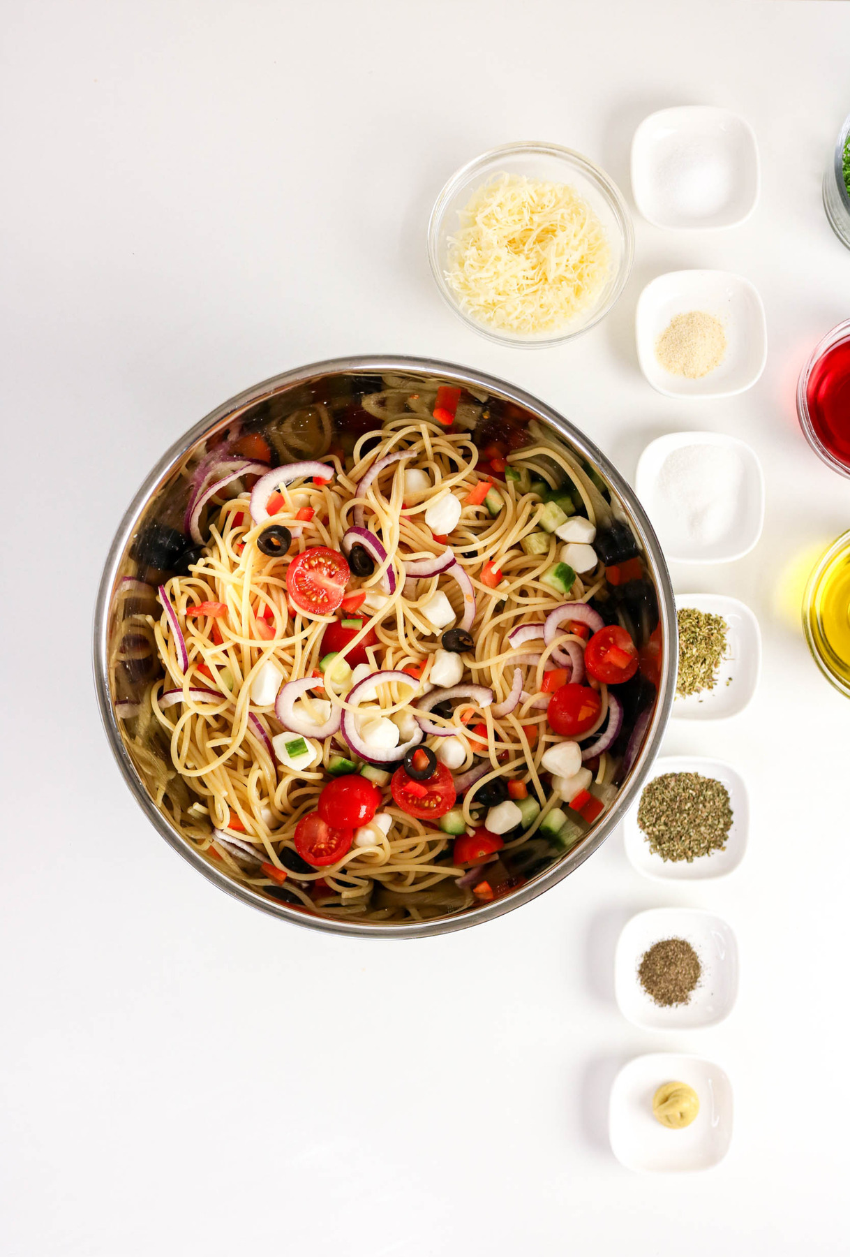 Cooked cooled pasta with tomatoes, olives, and mozarella pearls.