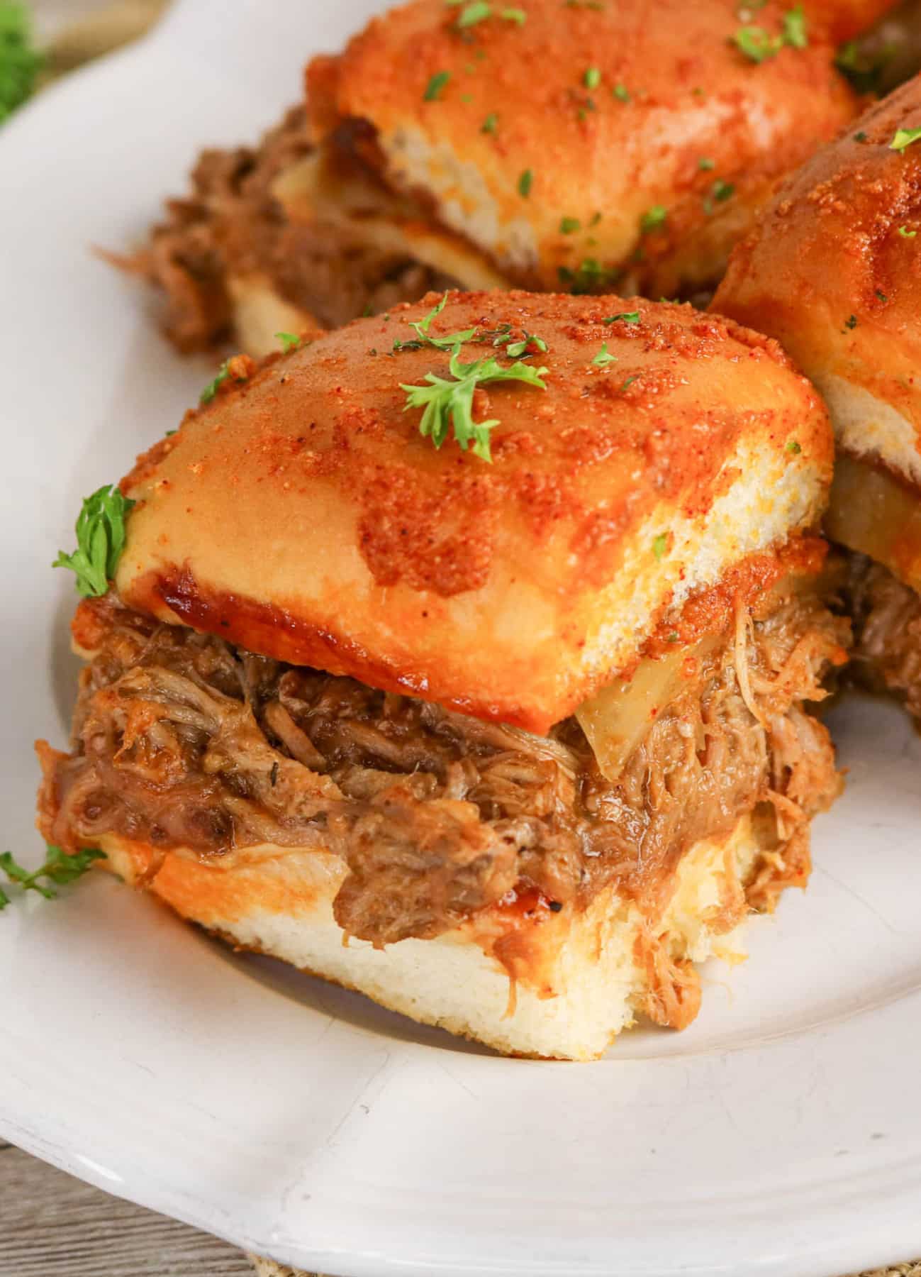 BBQ slider with shredded pulled pork on a white serving plate.