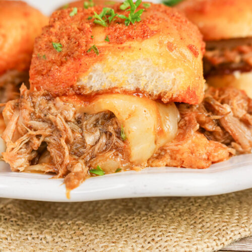 BBQ pulled pork sliders on a white serving plate.