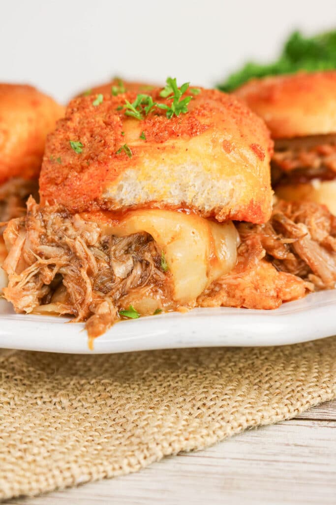 BBQ pulled pork sliders on a white serving plate.