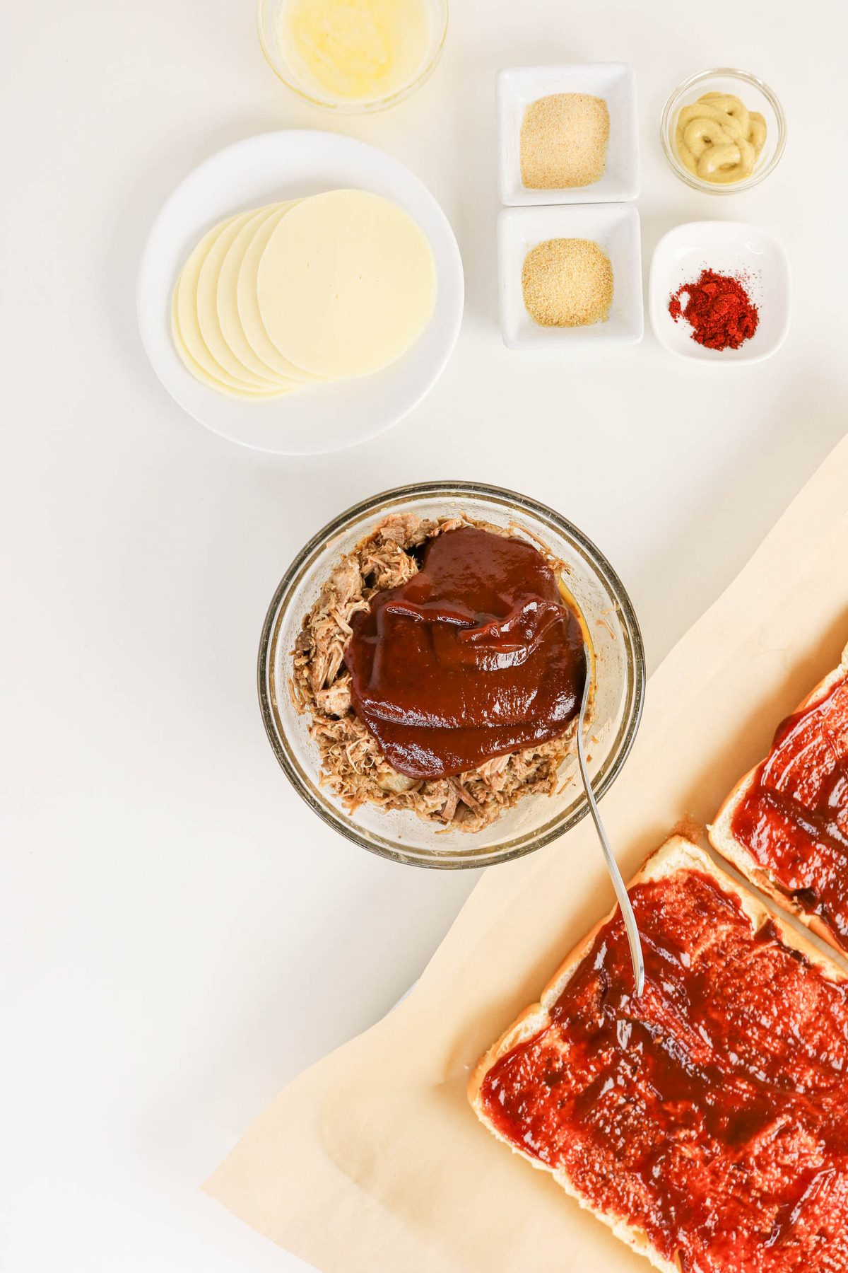 Pulled pork in a clear mixing bowl topped with BBQ sauce.