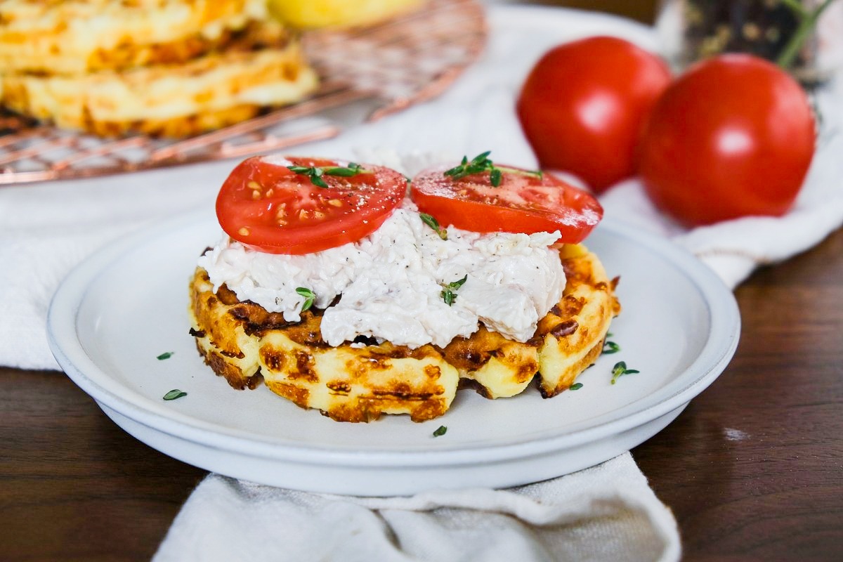A chaffle topped with chicken salad and tomatoes.