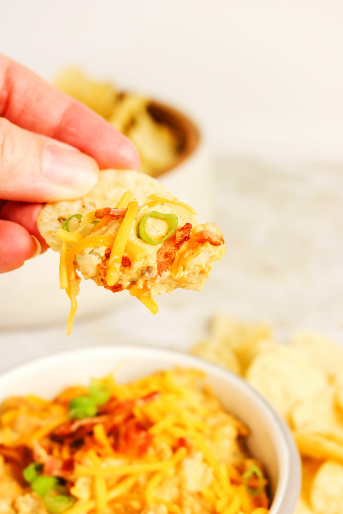 A scoop of cheeseburger dip on a tortilla chip.