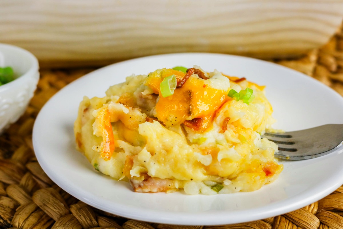 A scoop of twice baked mashed potatoes casserole on a serving plate.