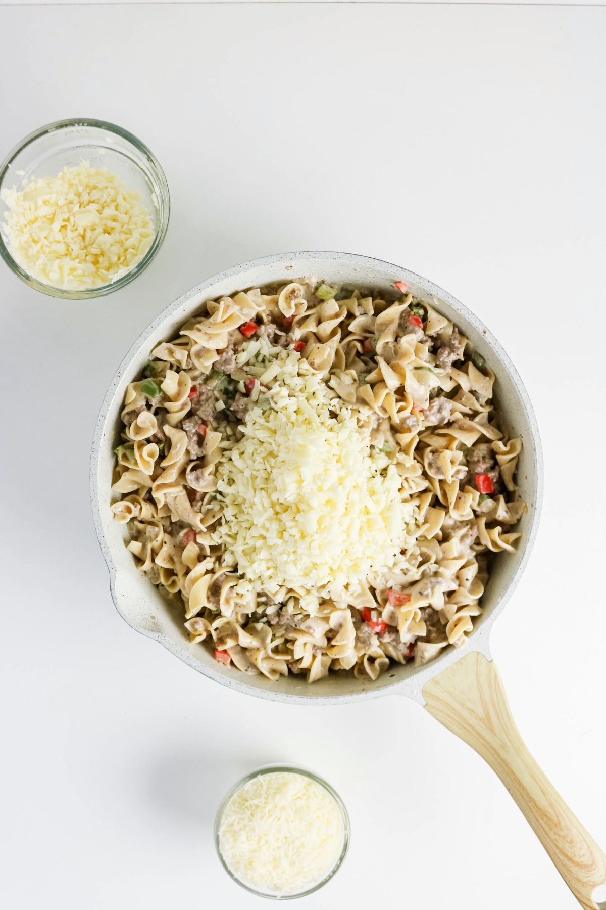 Cheese on top of noodle mixture in a skillet.