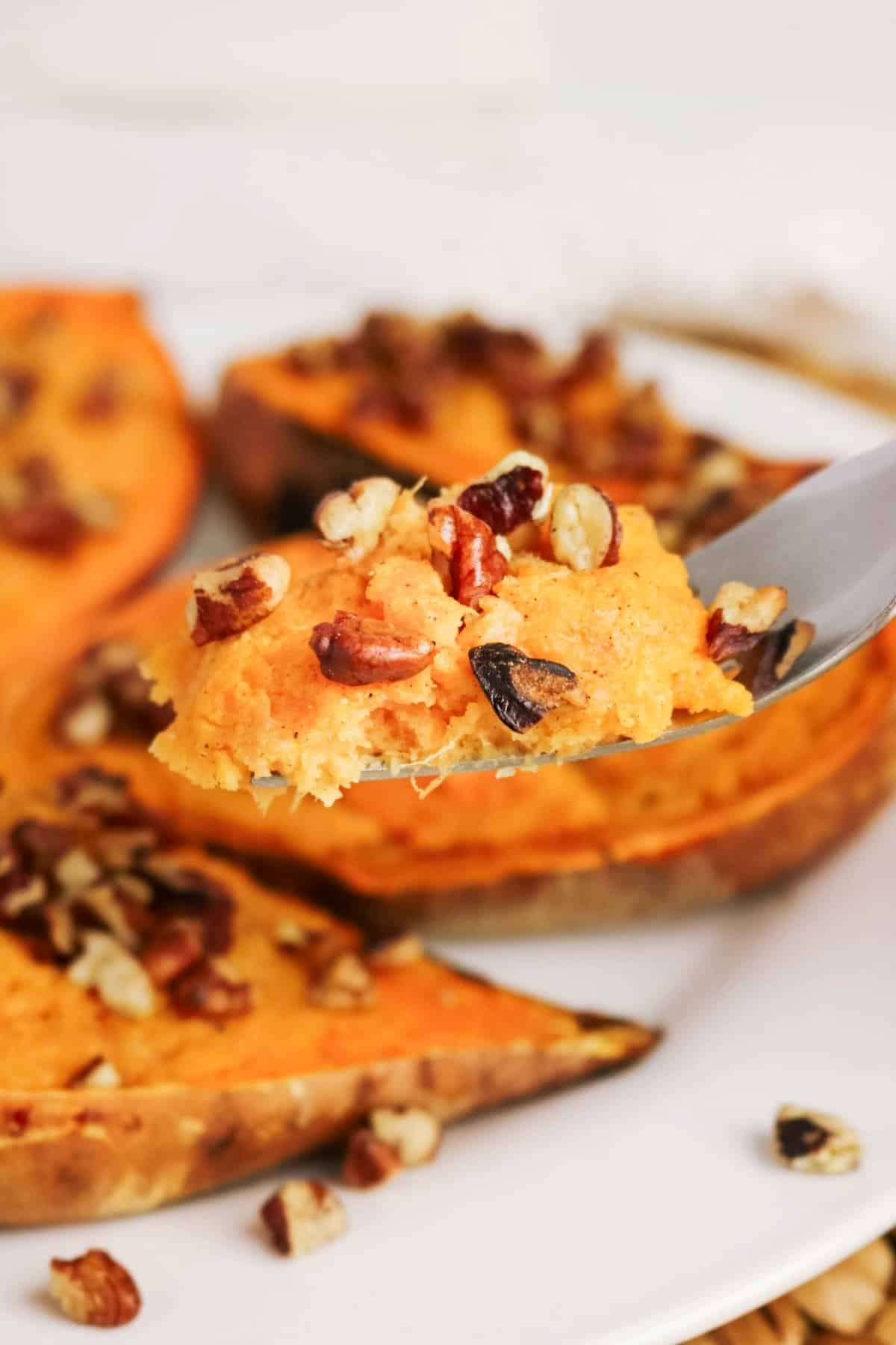 A forkful of sweet potatoes topped with pecans.