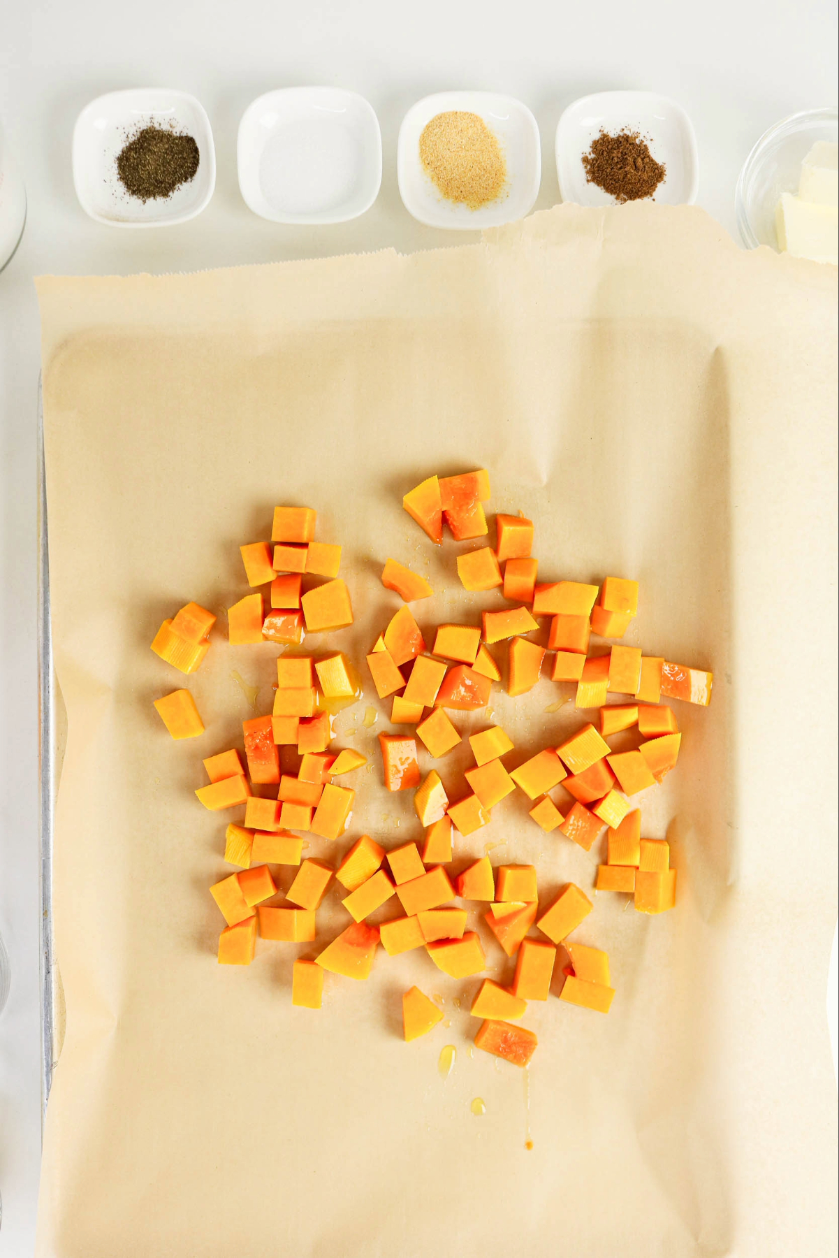 Diced butternut squash on a baking sheet before roasting.