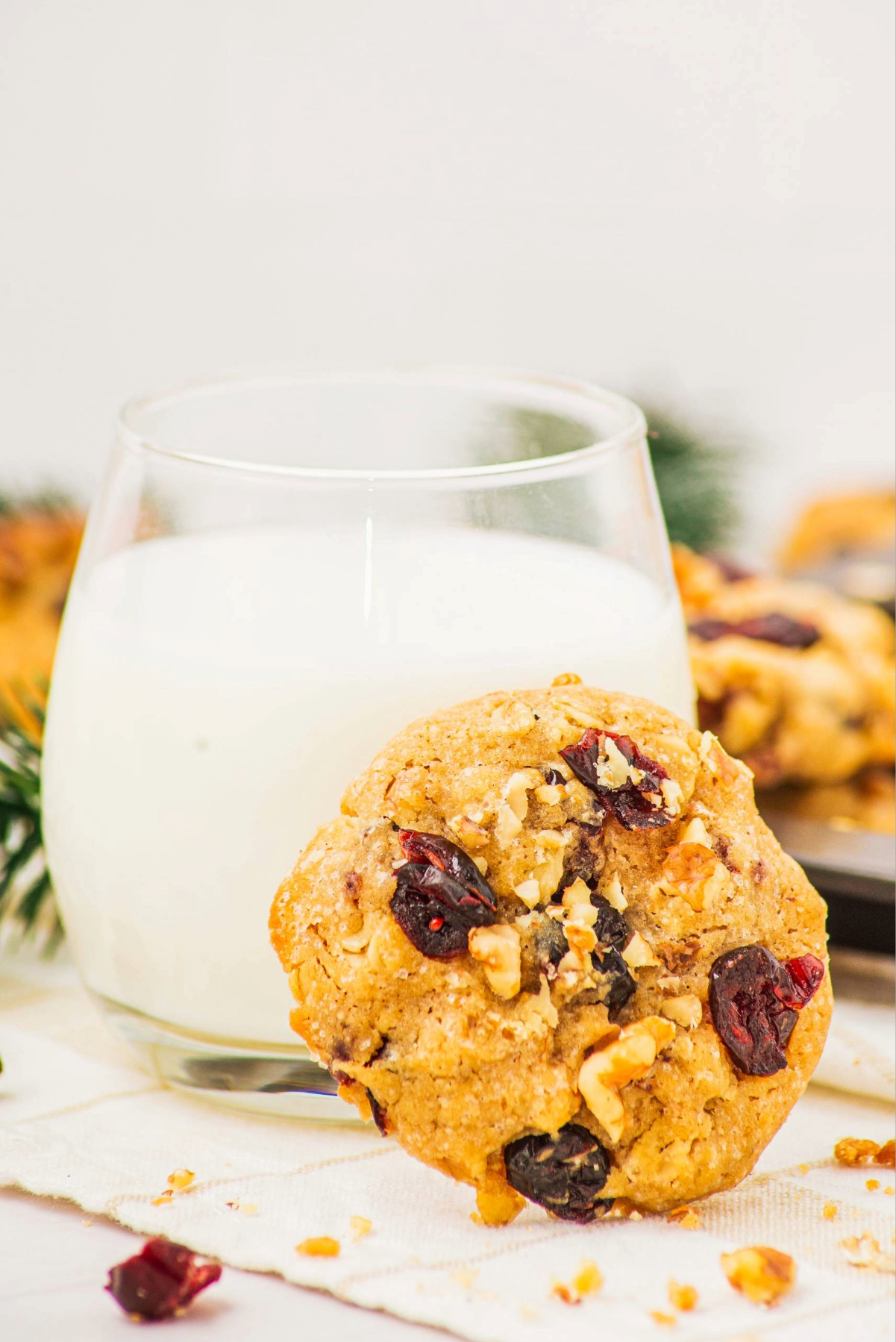 Baked cookie propped next to a clear glass of milk.