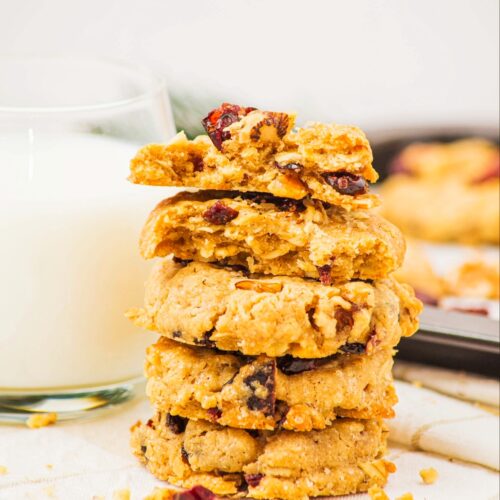 A stack of cranberry oatmeal cookies next to a glass of milk.