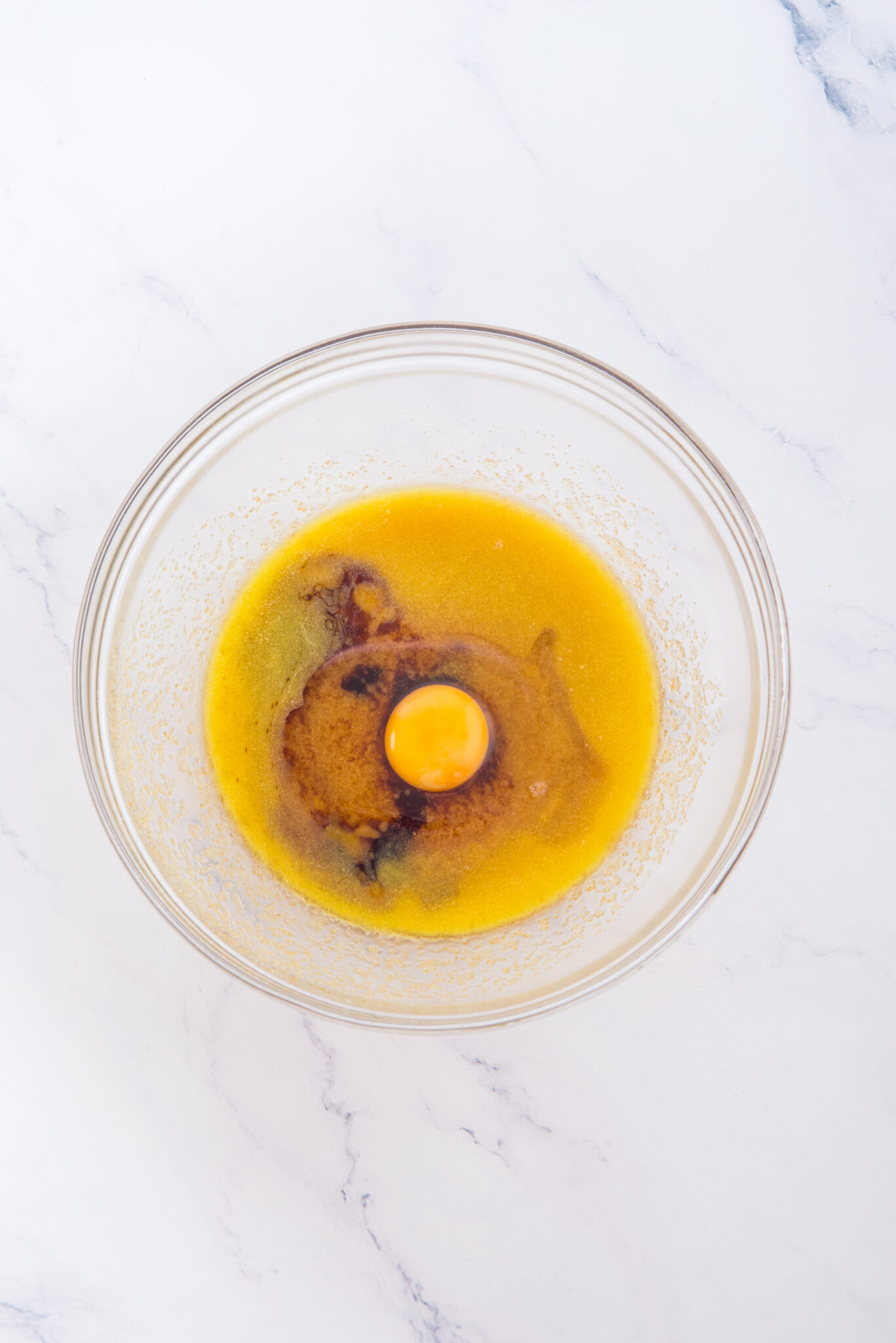 Wet ingredients in a mixing bowl with an egg before whisking together.
