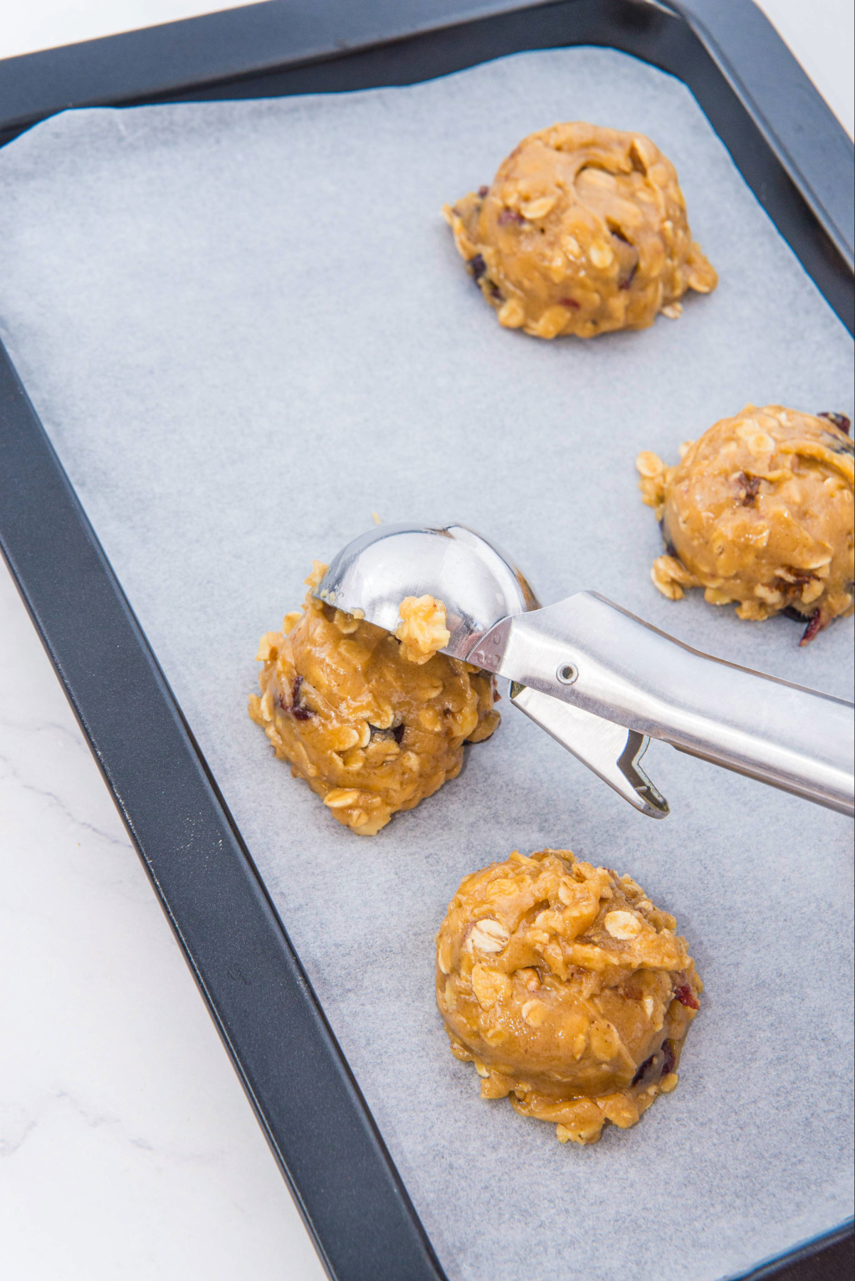 Cookie dough scooped on a baking sheet lined with parchment paper before baking.