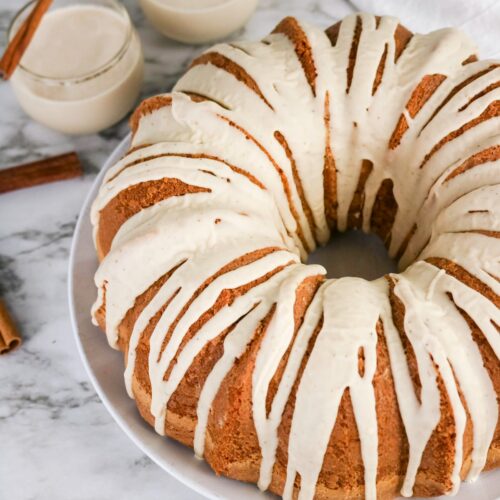 Eggnog cake on a white plate with drizzle on top of the cake.