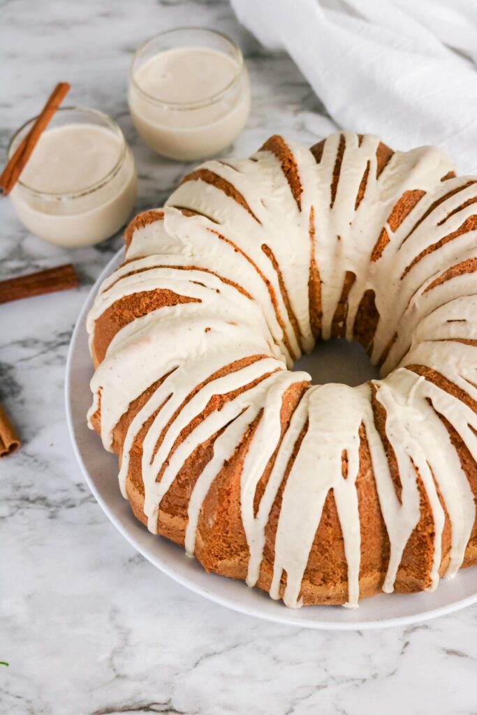 Eggnog cake on a white plate with drizzle on top of the cake.