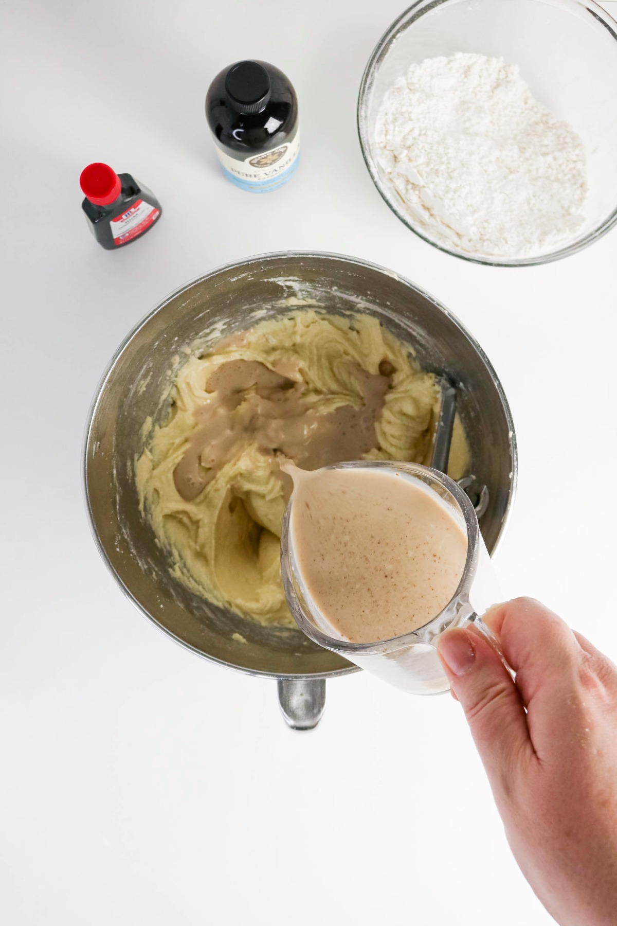 Pouring from a measuring cup eggnog into a batter mix.