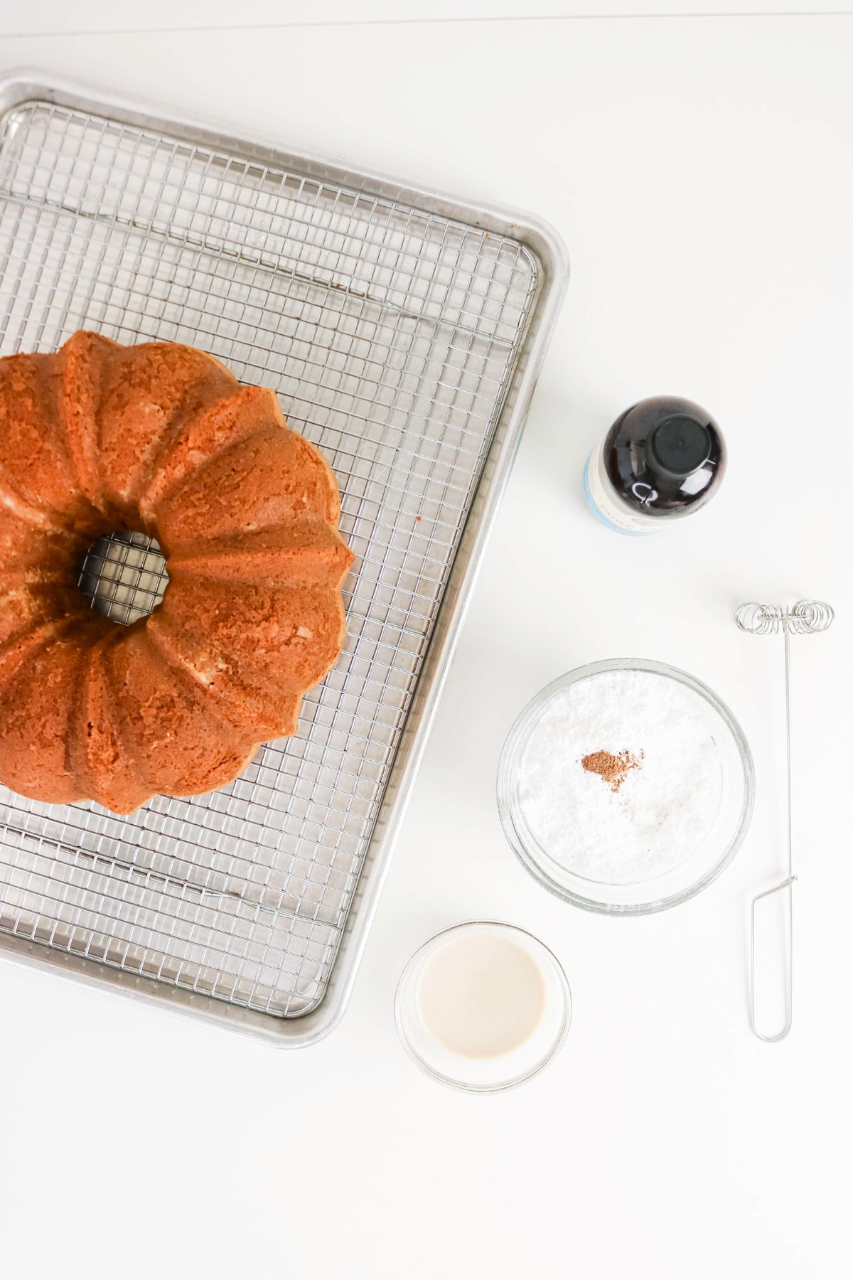 Cake cooling on a cooling rack with ingredients for a glaze on the side.