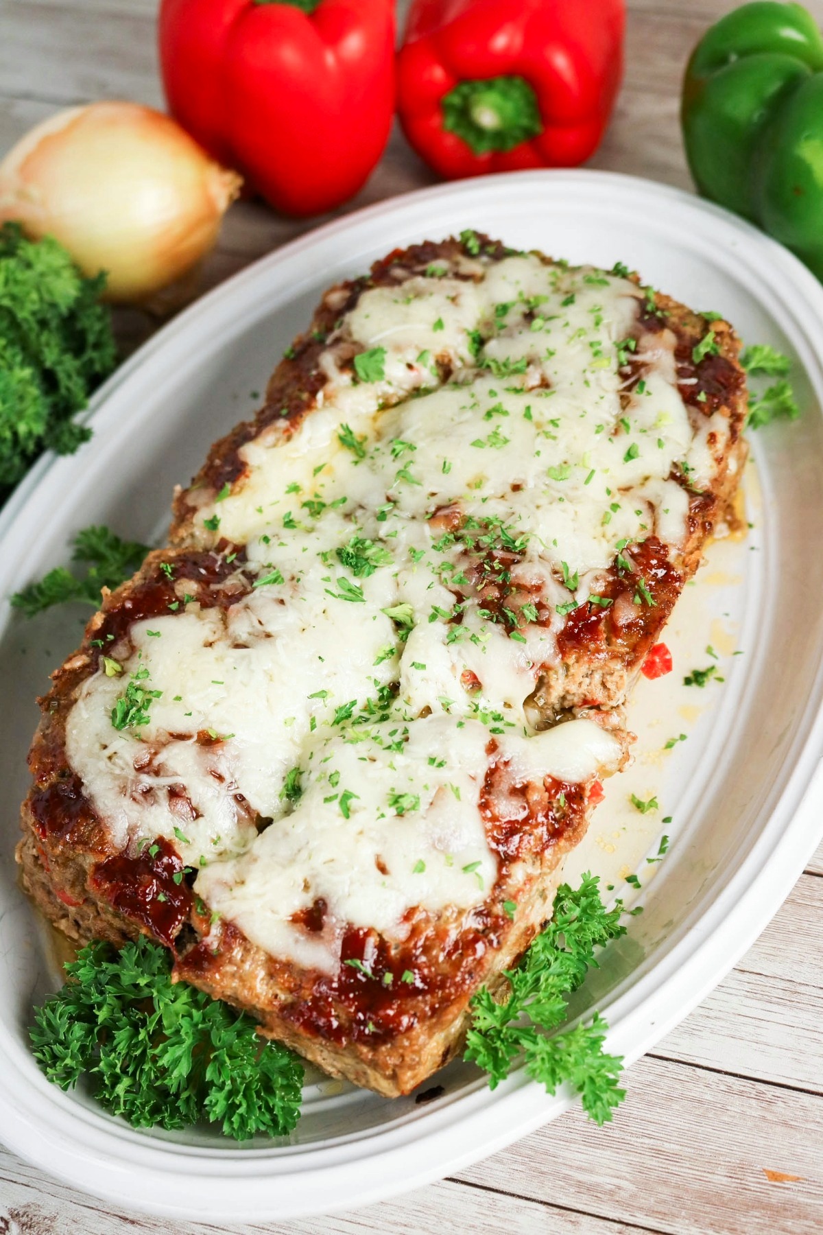 Whole meatloaf on a white platter with parsley before cutting.