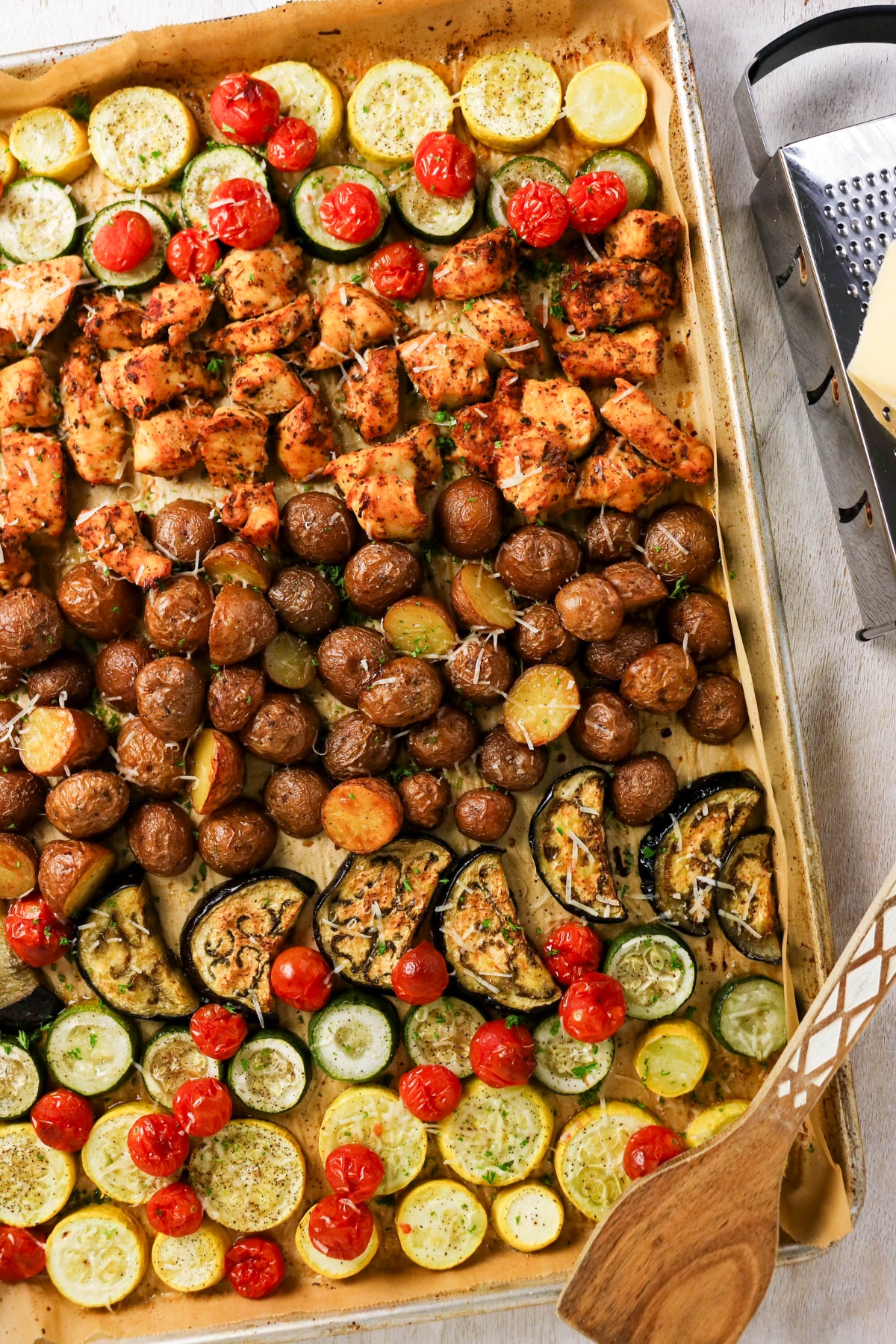 Roasted chicken and vegetables on a parchment lined baking sheet.
