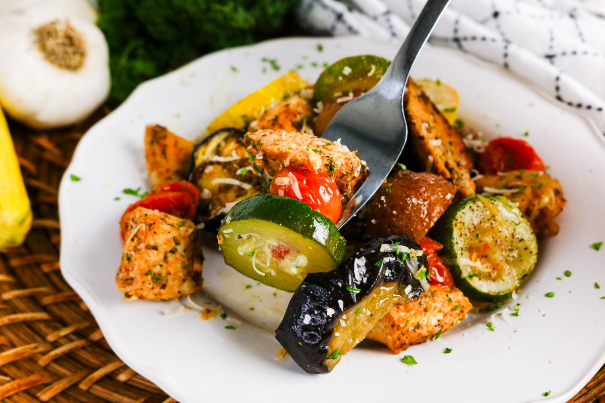 Dinner plate with chicken with a forkful of vegetables.
