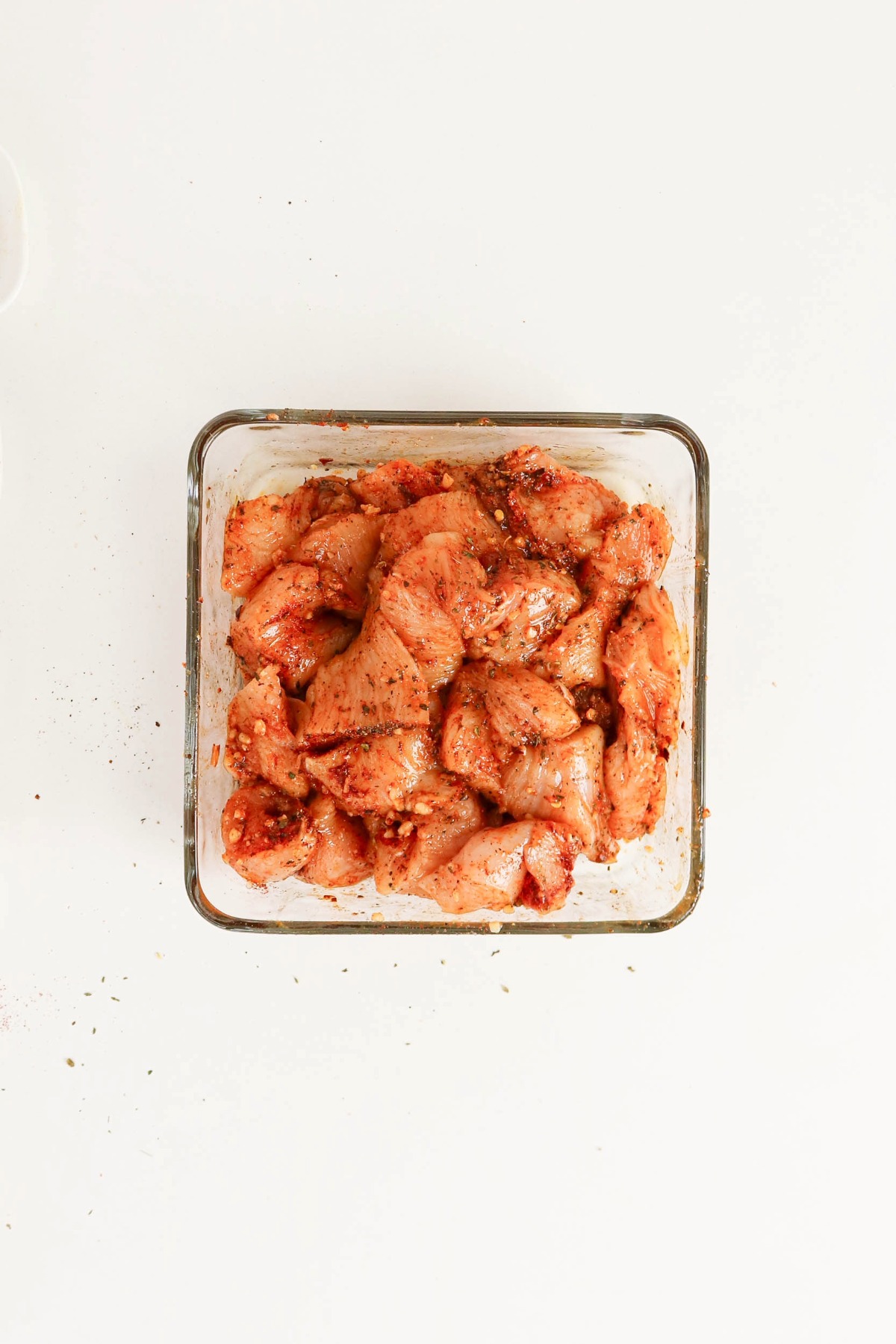 Seasoned diced chicken in a square clear dish.