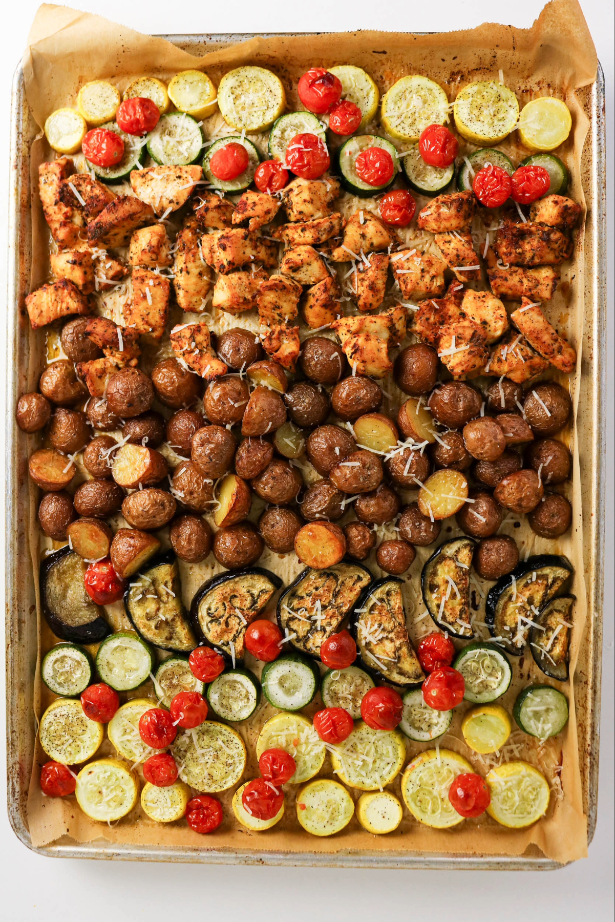 Cooked chicken with vegetables on a sheet pan.